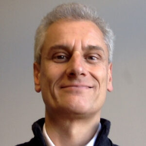 A man with grey hair smiling at camera