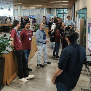 Visitors standing around posters at the Secure Systems Demo Day.